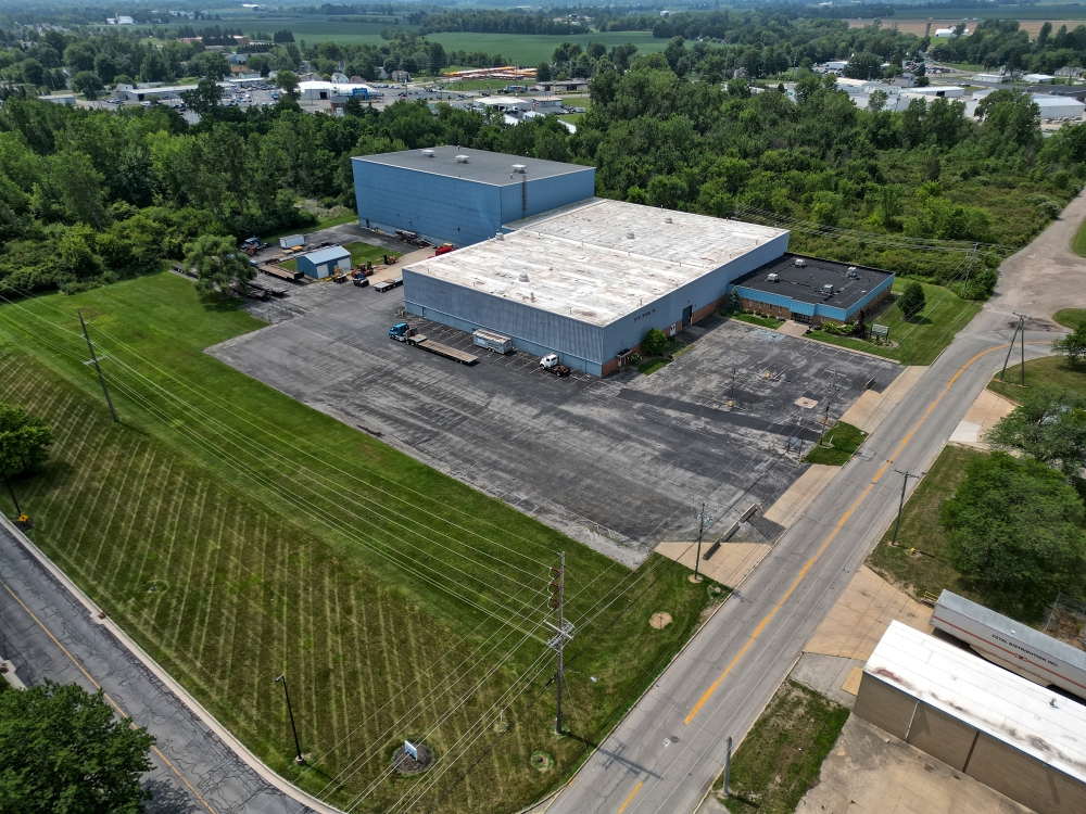 A drone captures an aerial view of an industrial building in a rural area.
