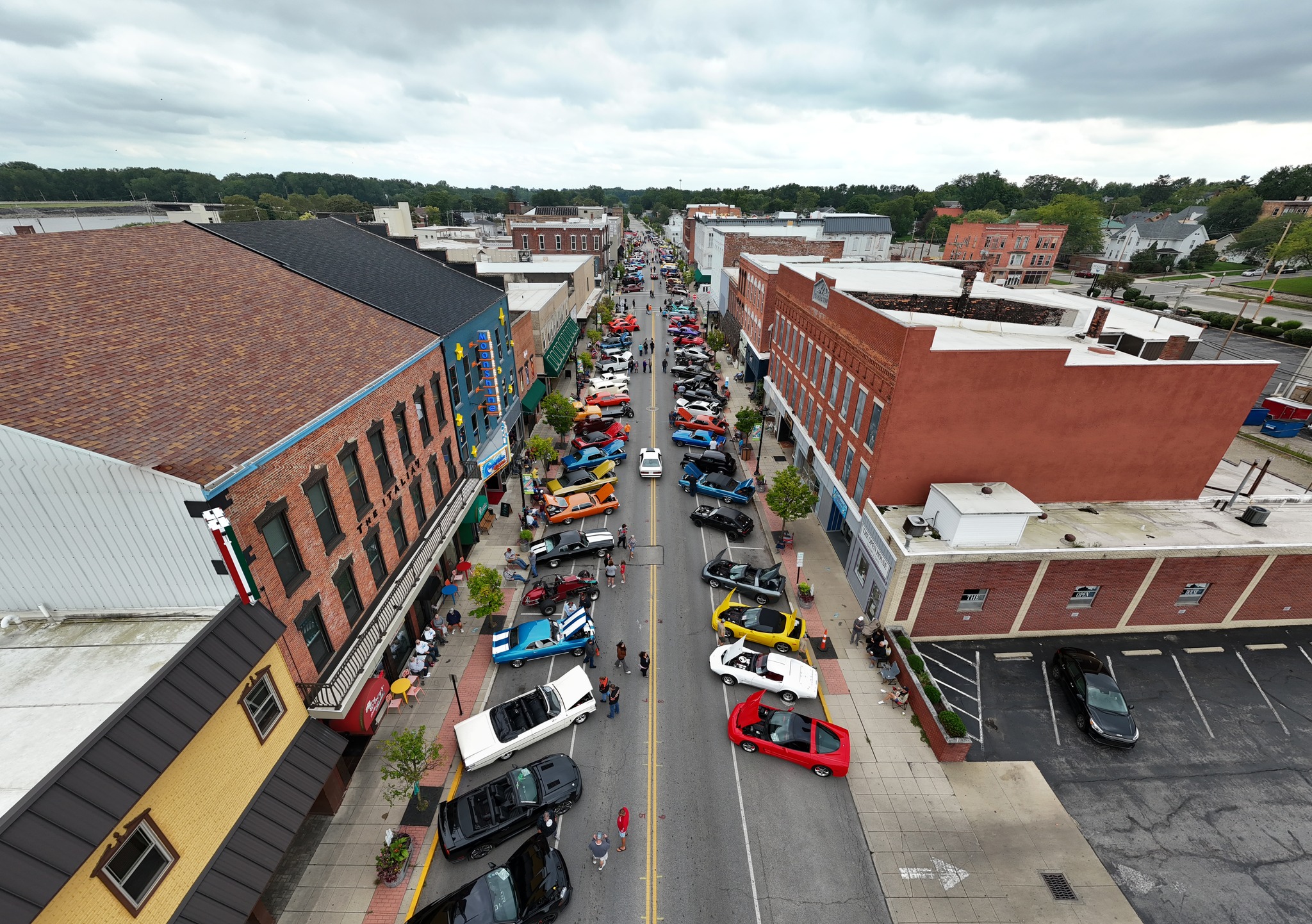  A street lined with parked cars and a building in the background, showcasing a car event with numerous classic cars.