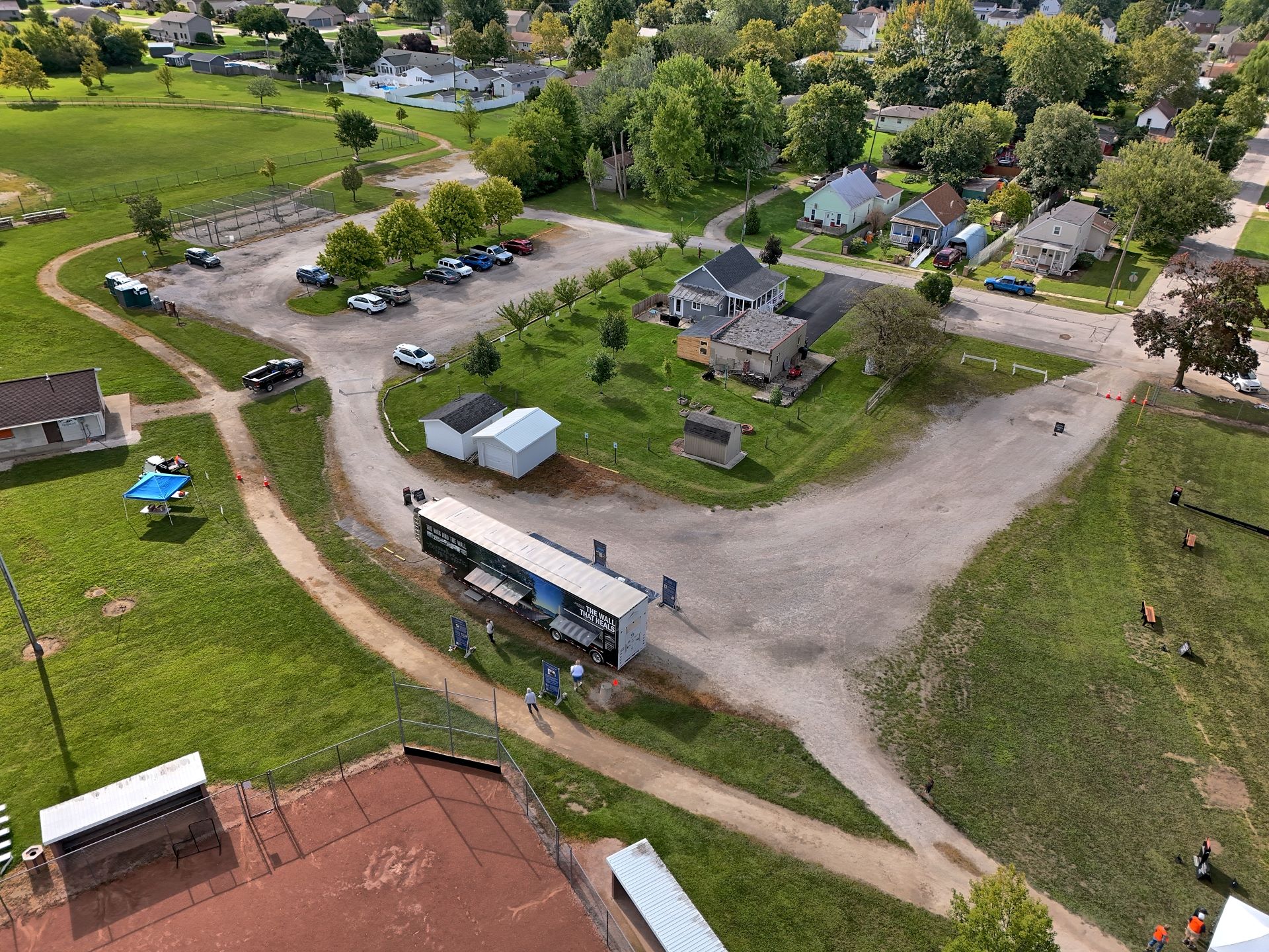 Aerial view of a park with a baseball field and a house surrounded by residential area.